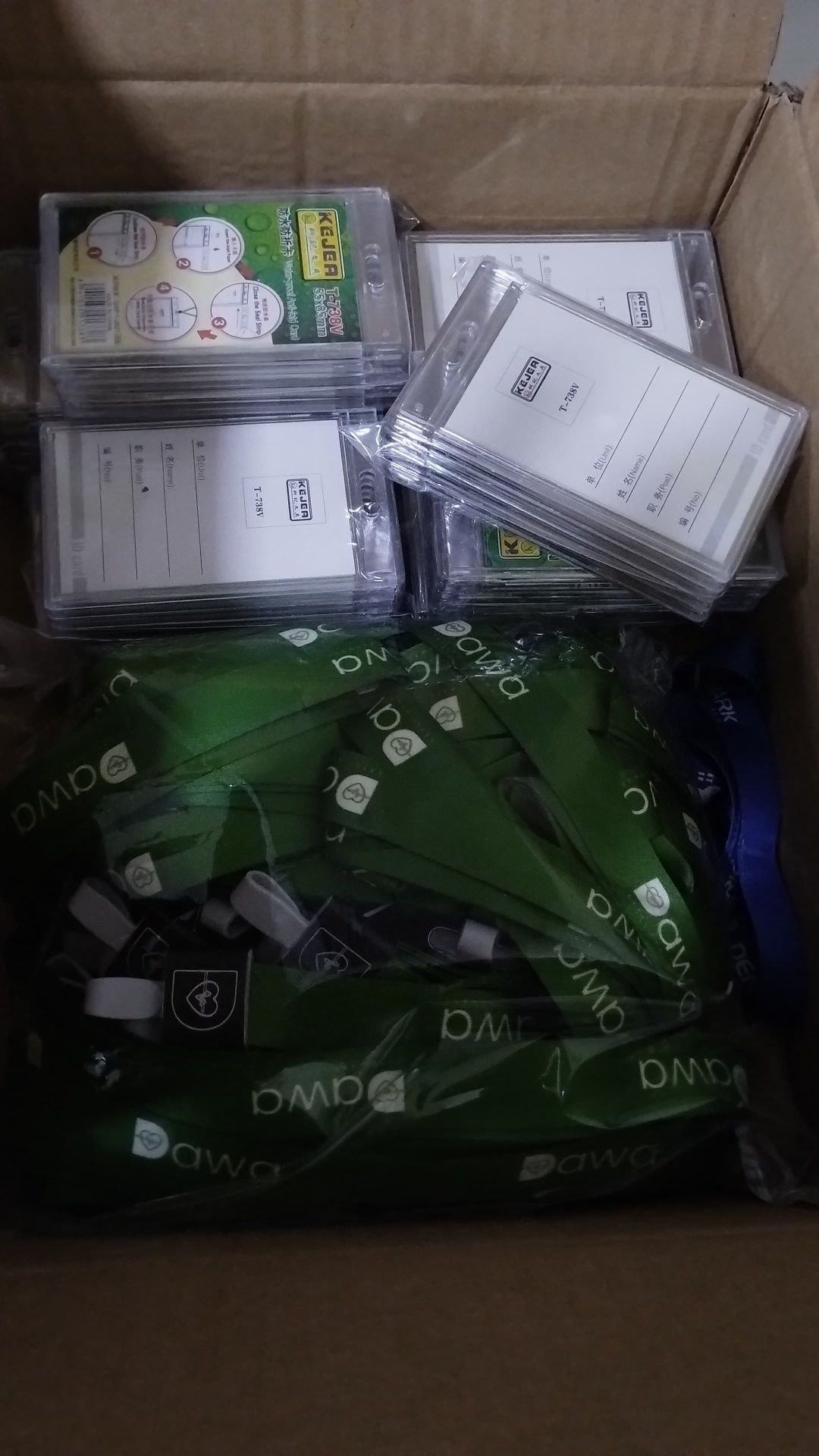 Customer photo of stacked ID card holders and green branded lanyards in a carton